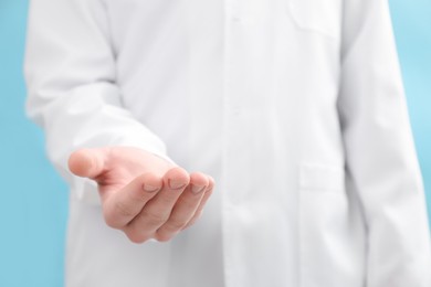 Photo of Doctor holding something on light blue background, selective focus