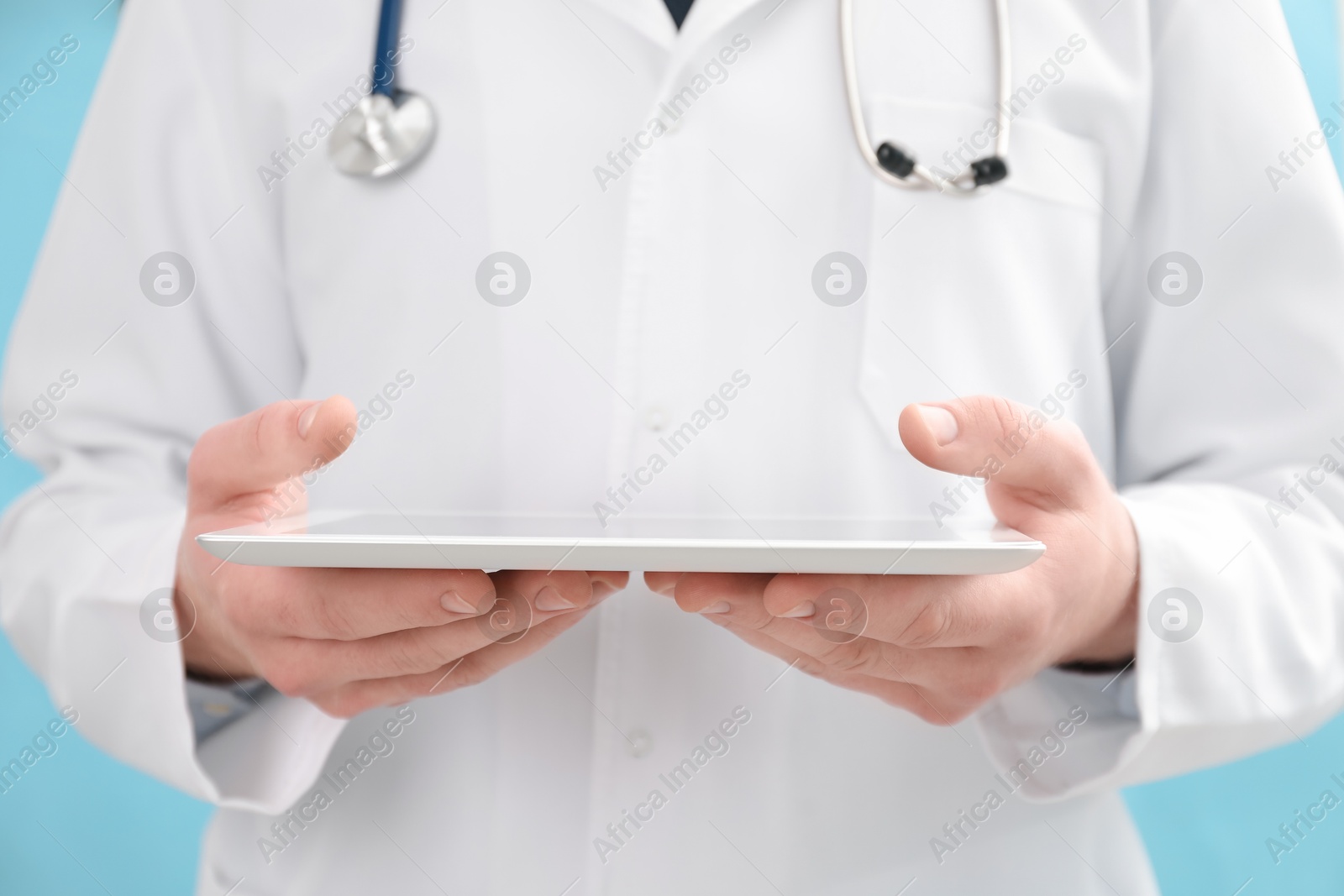 Photo of Doctor with tablet on light blue background, selective focus