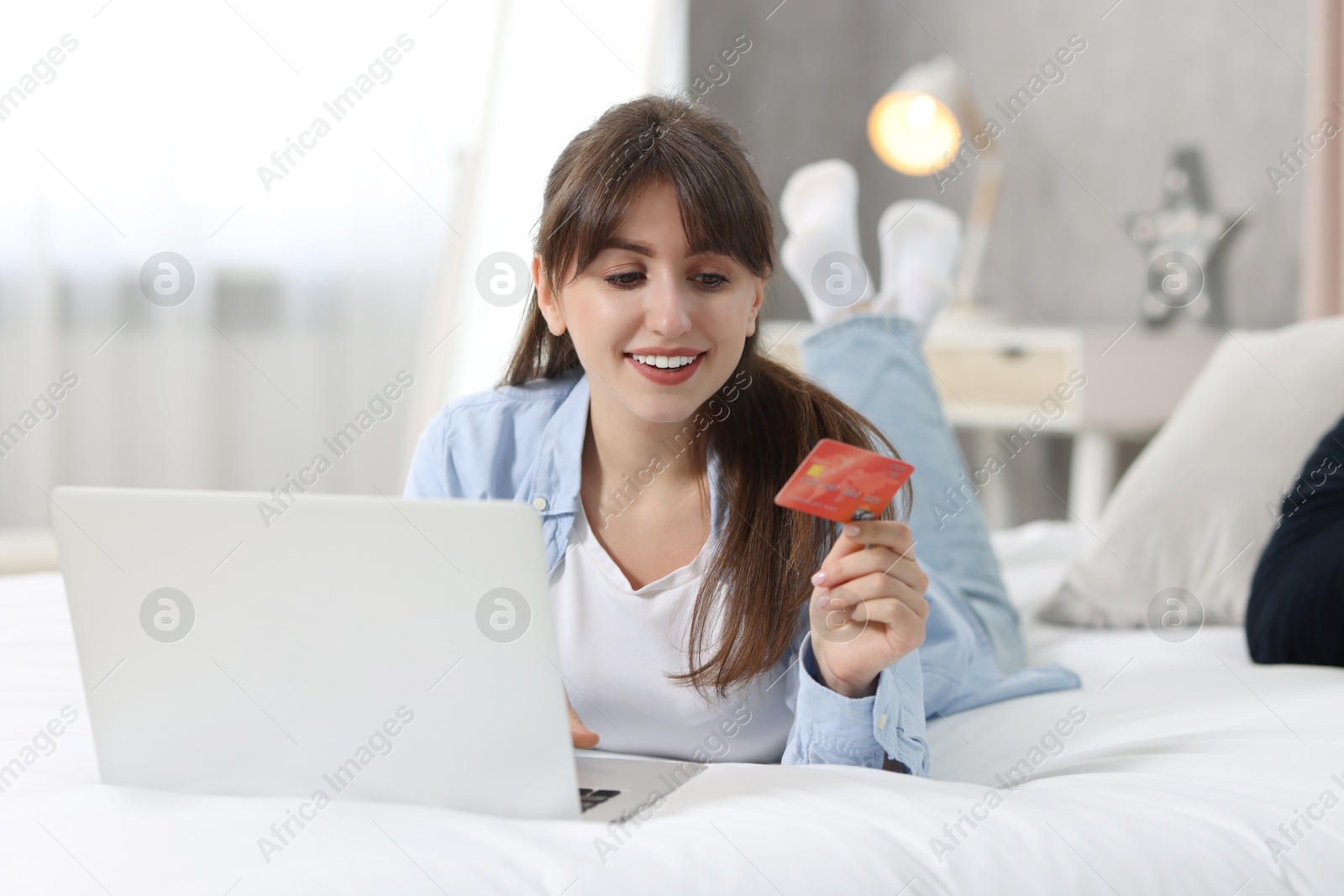 Photo of Online banking. Smiling woman with credit card and laptop paying purchase at home