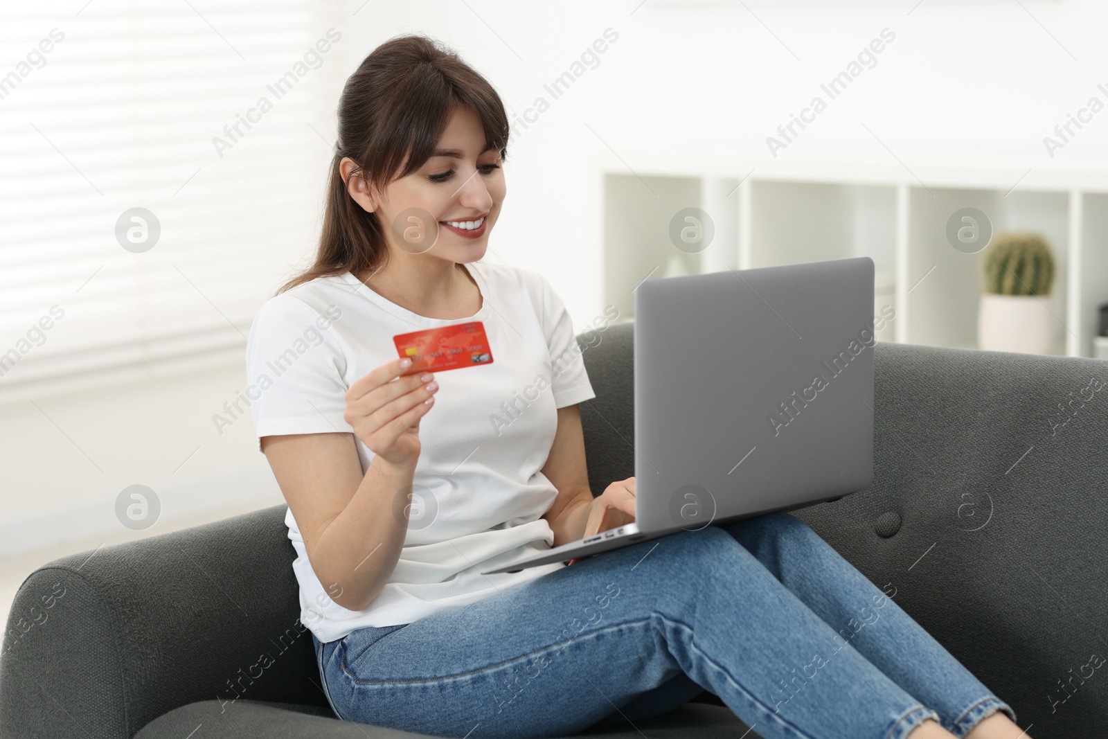 Photo of Online banking. Smiling woman with credit card and laptop paying purchase at home