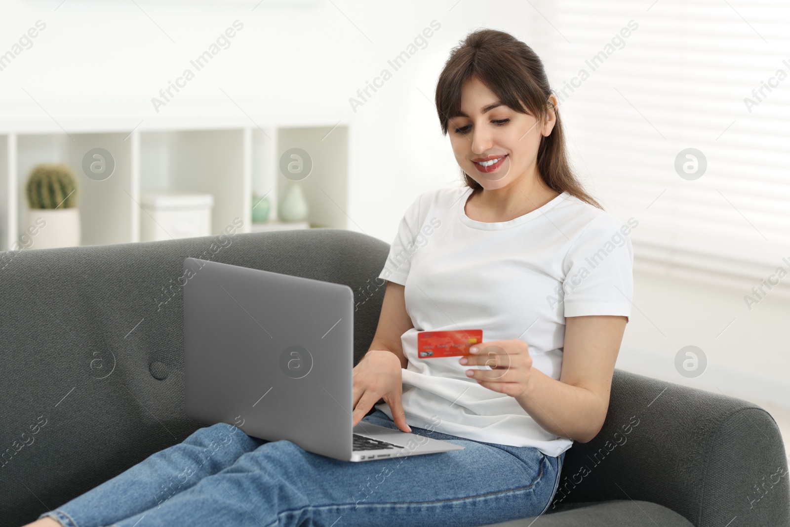 Photo of Online banking. Smiling woman with credit card and laptop paying purchase at home