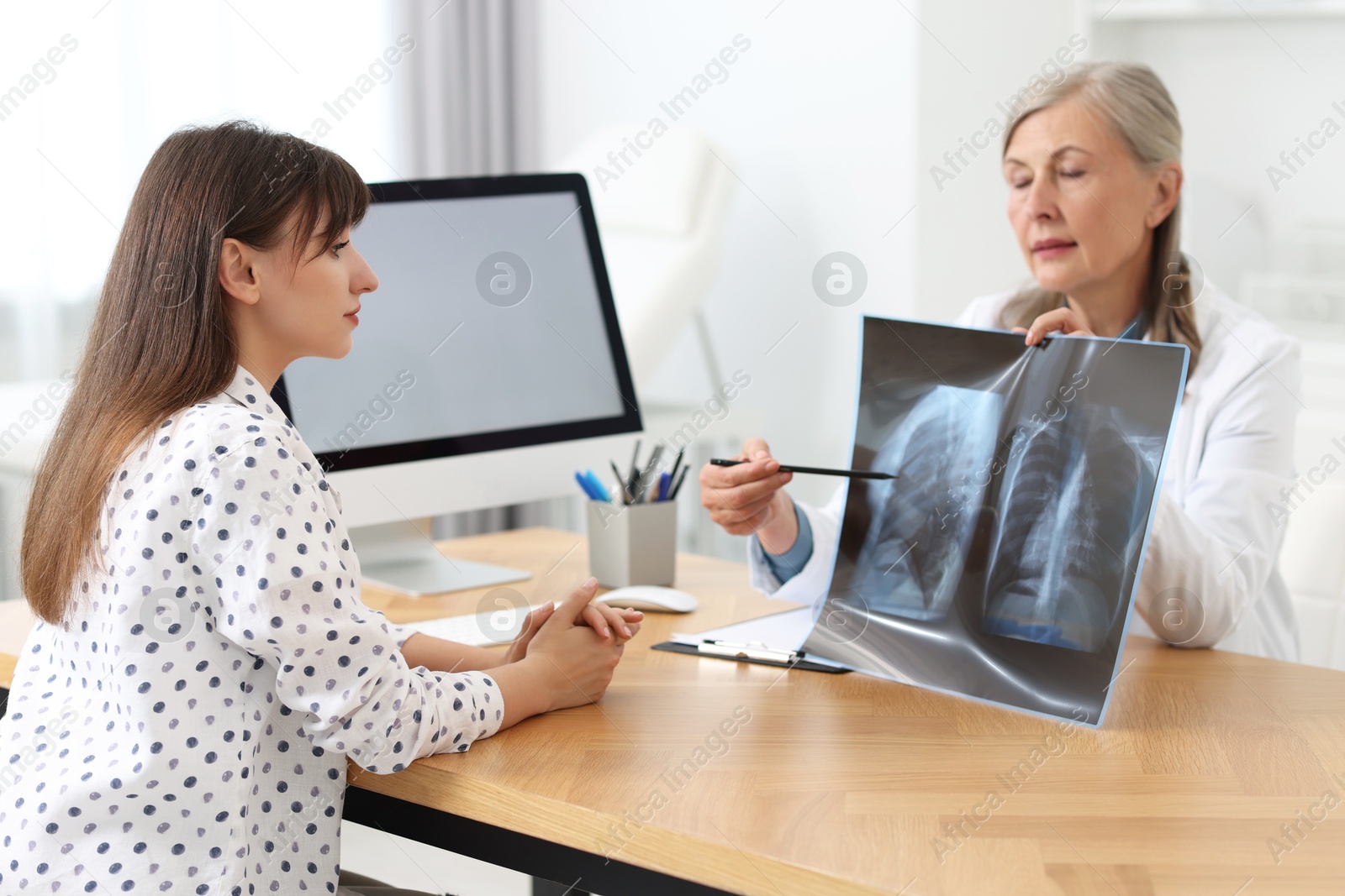 Photo of Lung disease. Doctor showing chest x-ray to her patient in clinic