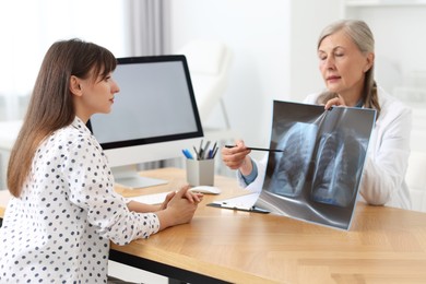 Lung disease. Doctor showing chest x-ray to her patient in clinic