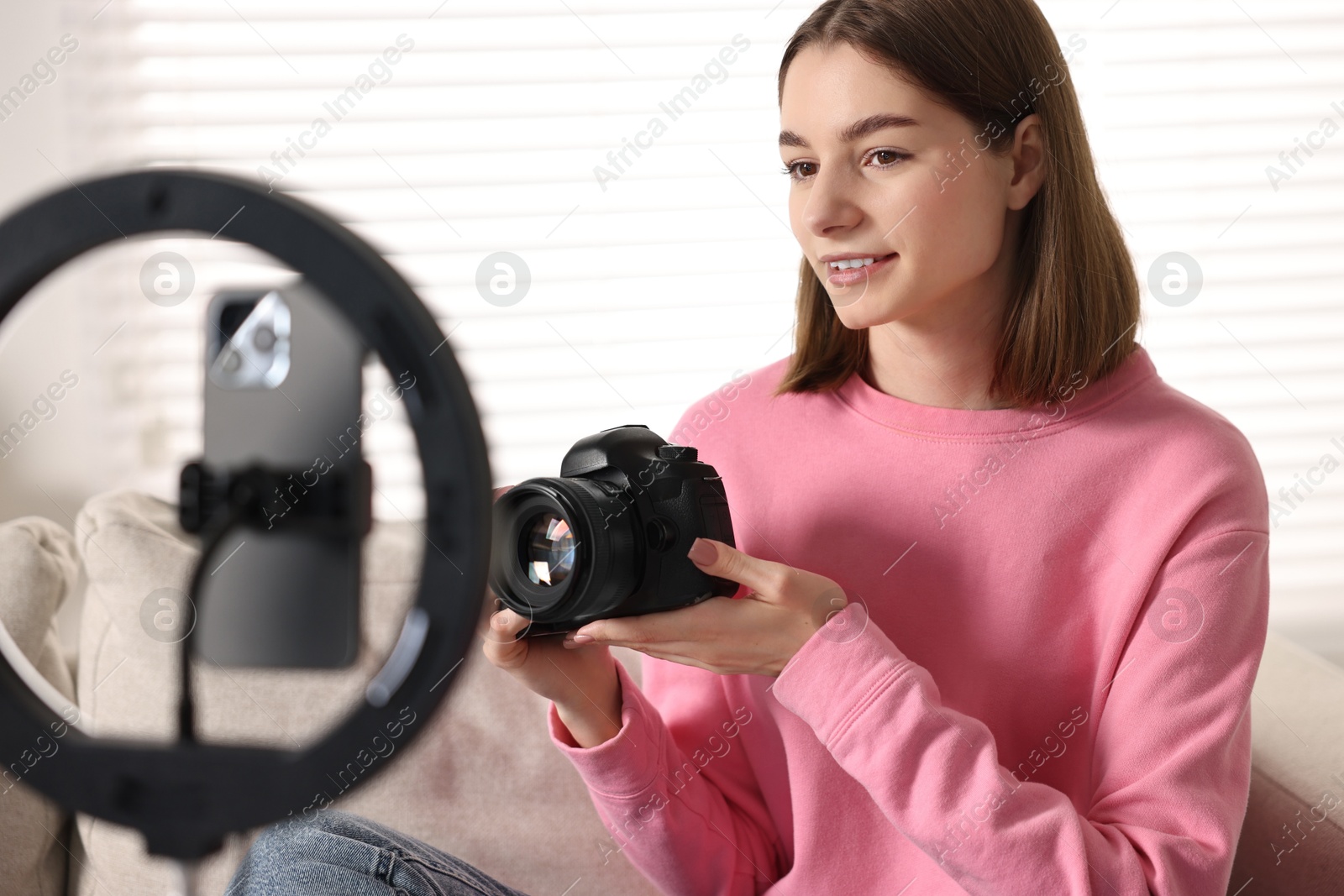 Photo of Technology blogger reviewing camera and recording video with smartphone and ring lamp at home