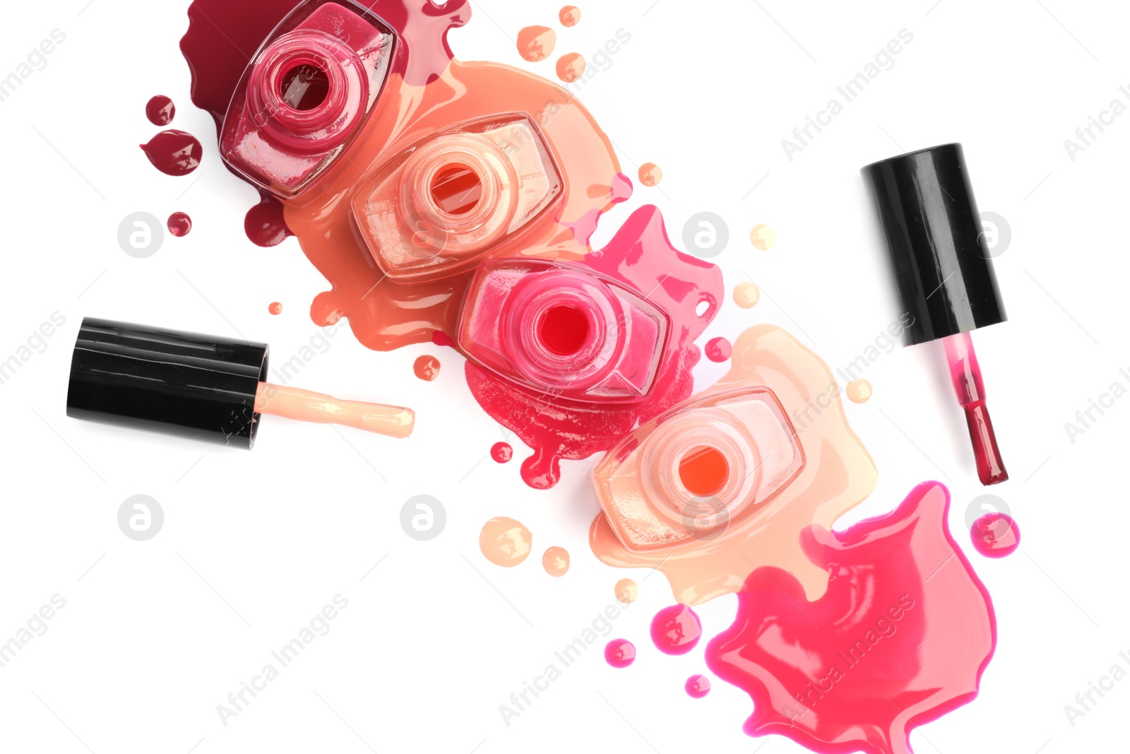 Photo of Many bottles, brushes and drops of colorful nail polishes isolated on white, top view