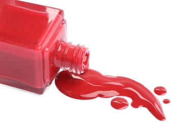 Bottle and spilled red nail polish isolated on white