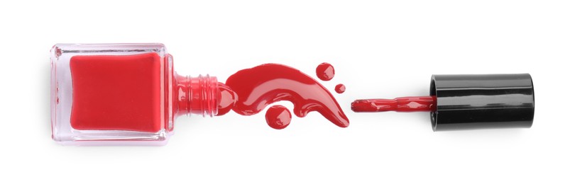 Photo of Bottle, brush and spilled red nail polish isolated on white, top view