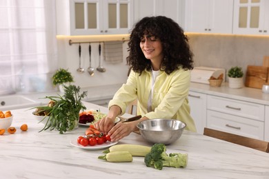 Woman cooking healthy vegetarian meal at white marble table in kitchen