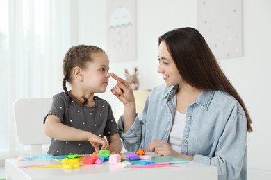 Photo of Play dough activity. Smiling mother with her daughter at table indoors
