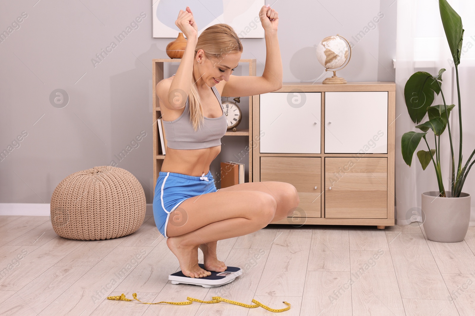 Photo of Happy woman on floor scale at home