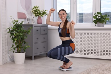 Photo of Happy woman on floor scale at home