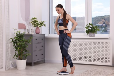 Woman stepping on floor scale at home