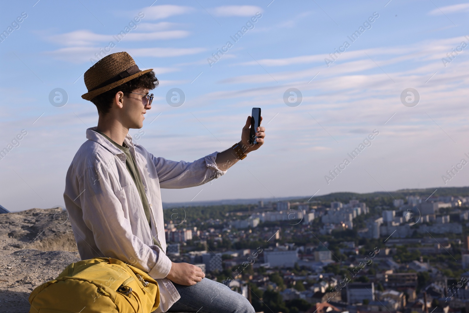 Photo of Travel blogger in sunglasses takIng selfie with smartphone outdoors, space for text