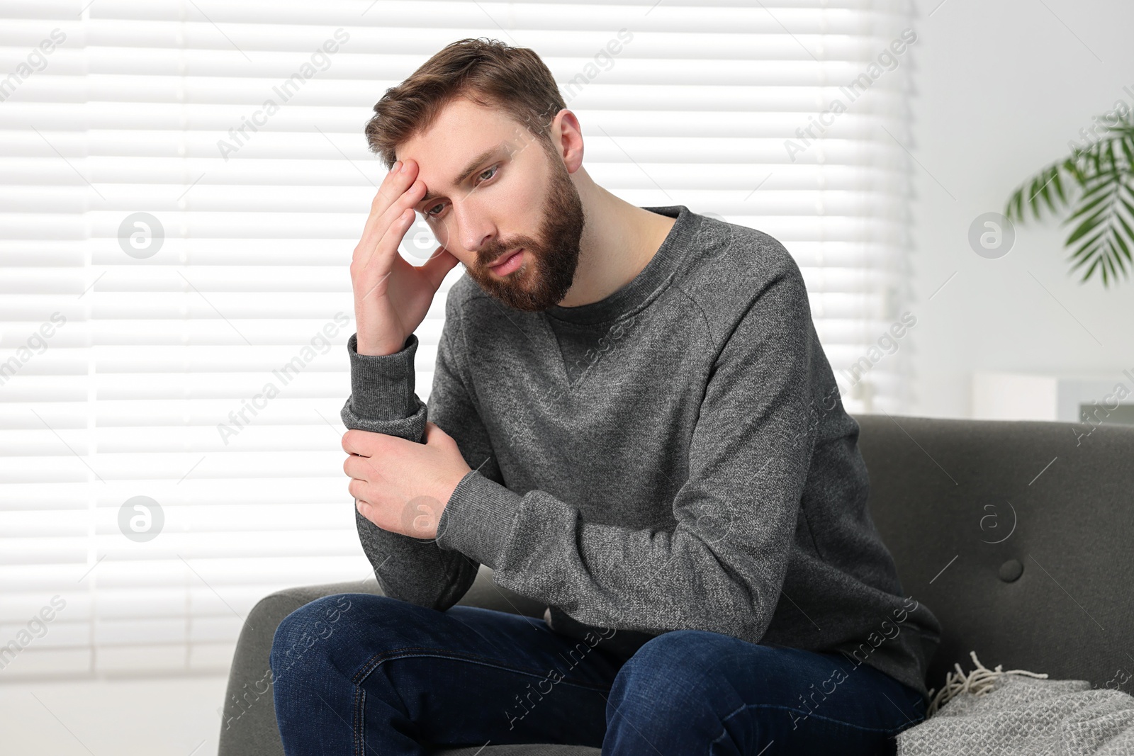 Photo of Loneliness concept. Sad man sitting on sofa at home