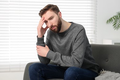 Loneliness concept. Sad man sitting on sofa at home