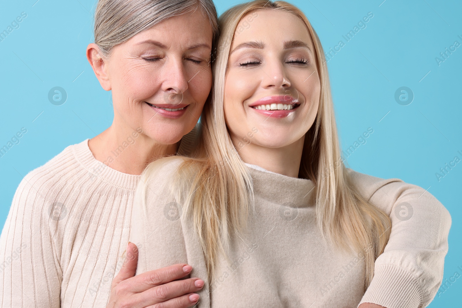 Photo of Family portrait of young woman and her mother on light blue background