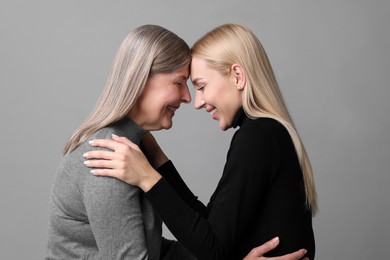 Photo of Family portrait of young woman and her mother on grey background