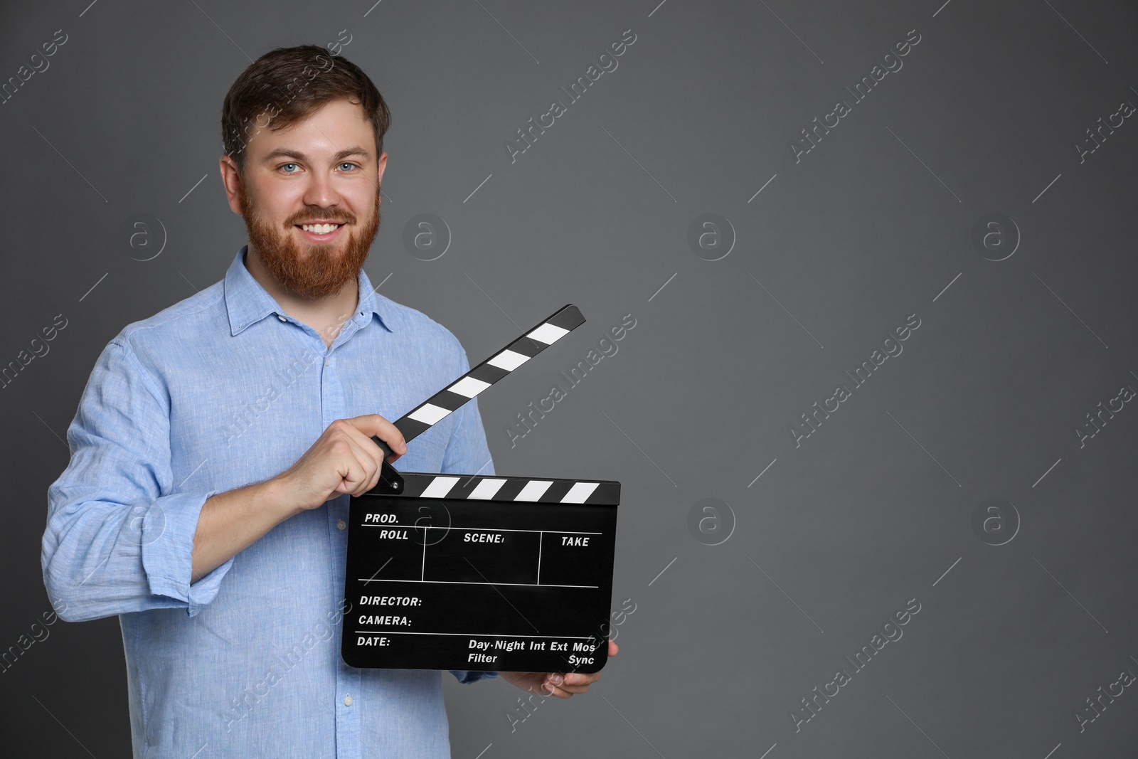 Photo of Making movie. Smiling man with clapperboard on grey background. Space for text