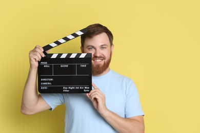 Photo of Making movie. Smiling man with clapperboard on yellow background