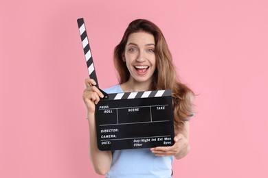 Photo of Making movie. Excited woman with clapperboard on pink background