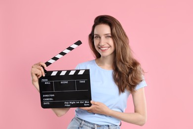 Photo of Making movie. Smiling woman with clapperboard on pink background