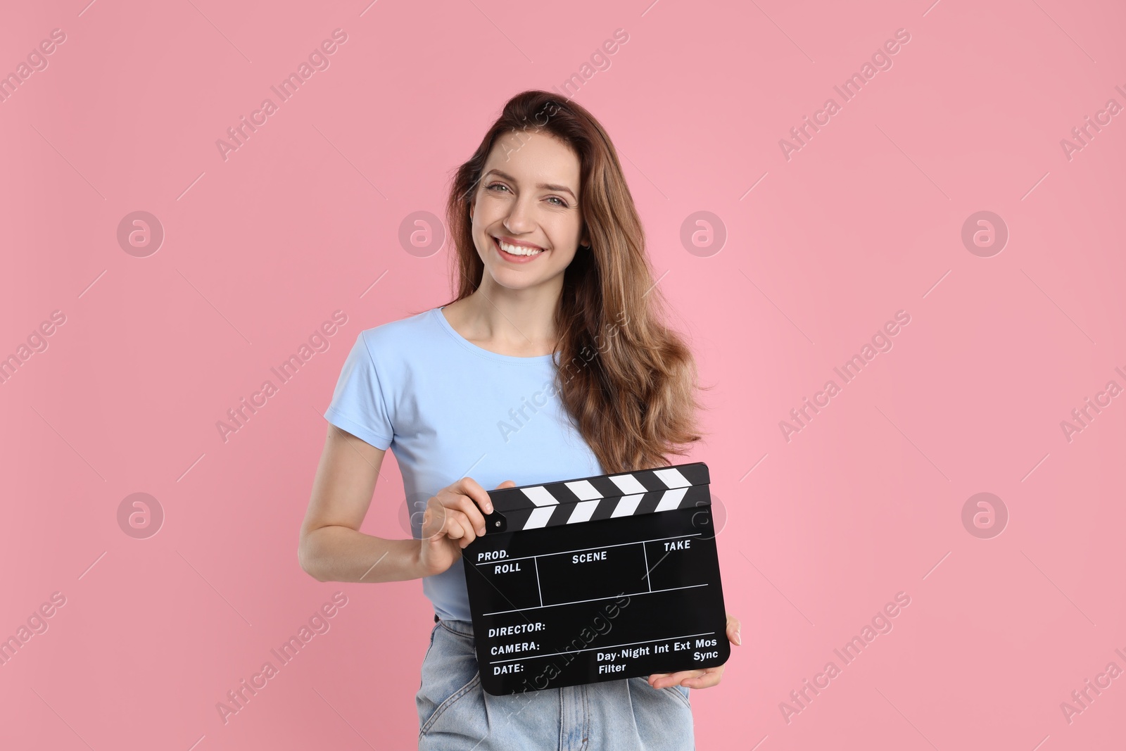 Photo of Making movie. Smiling woman with clapperboard on pink background