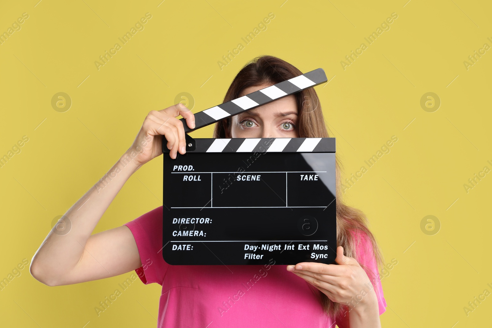 Photo of Making movie. Woman with clapperboard on yellow background