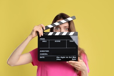 Making movie. Woman with clapperboard on yellow background