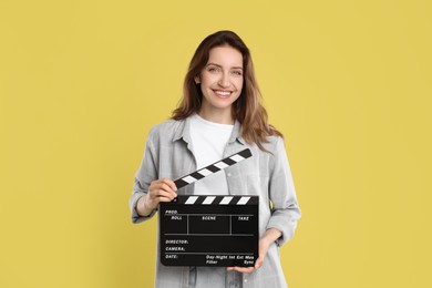 Making movie. Smiling woman with clapperboard on yellow background