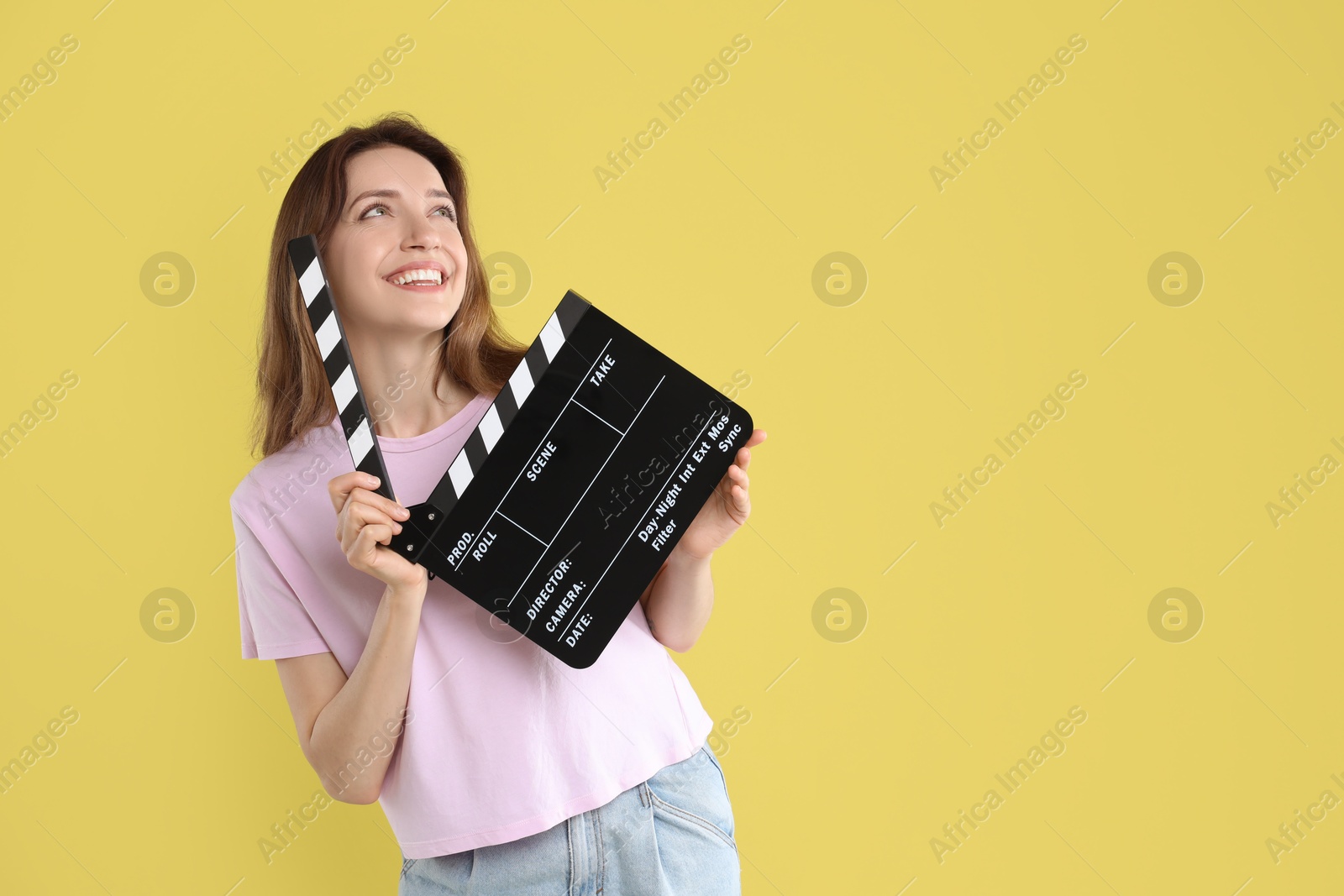 Photo of Making movie. Smiling woman with clapperboard on yellow background. Space for text