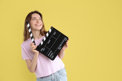 Making movie. Smiling woman with clapperboard on yellow background. Space for text