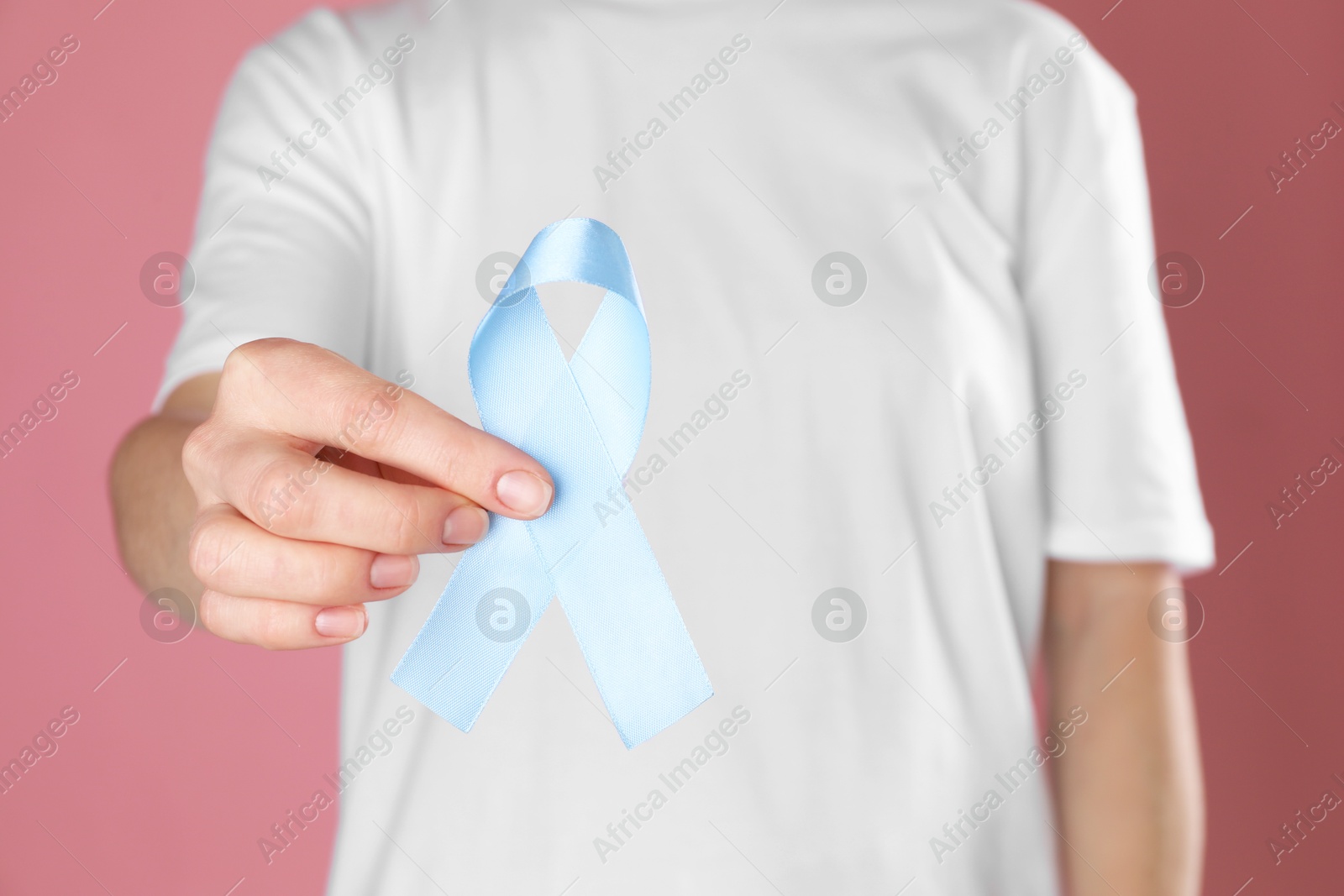 Photo of International Psoriasis Day. Woman with light blue ribbon as symbol of support on pink background, closeup
