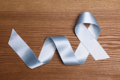 Photo of International Psoriasis Day. Ribbon as symbol of support on wooden table, top view