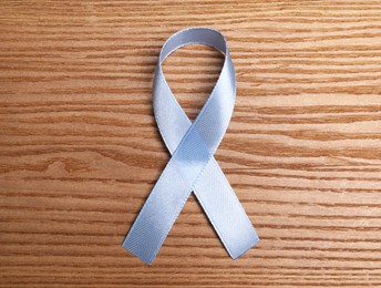 Photo of International Psoriasis Day. Ribbon as symbol of support on wooden table, top view