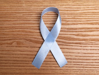 International Psoriasis Day. Ribbon as symbol of support on wooden table, top view