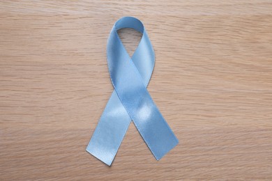 Photo of International Psoriasis Day. Ribbon as symbol of support on wooden table, top view