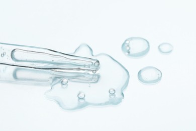 Glass pipette and transparent liquid on light background, closeup