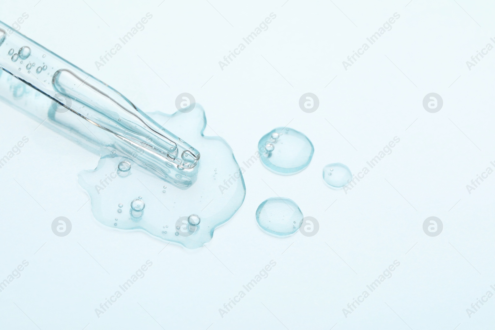 Photo of Glass pipette and transparent liquid on light background, top view