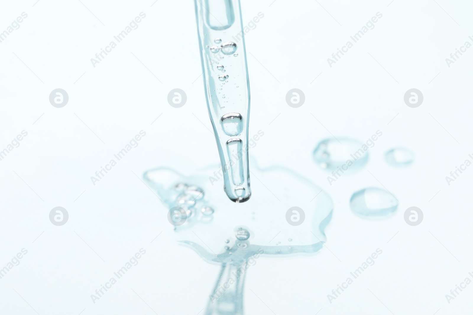 Photo of Glass pipette and transparent liquid on light background, closeup