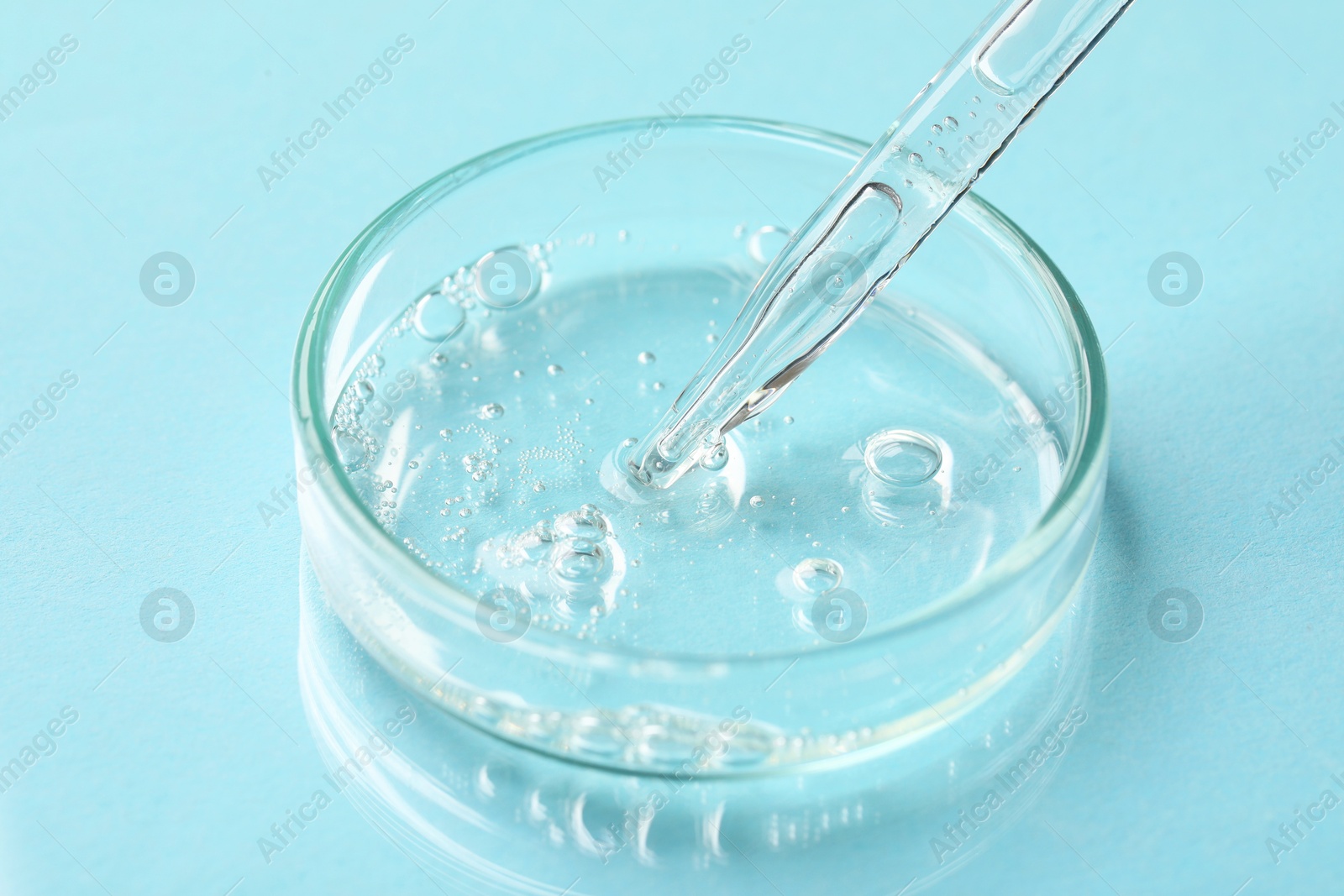 Photo of Glass pipette and petri dish with liquid on light blue background