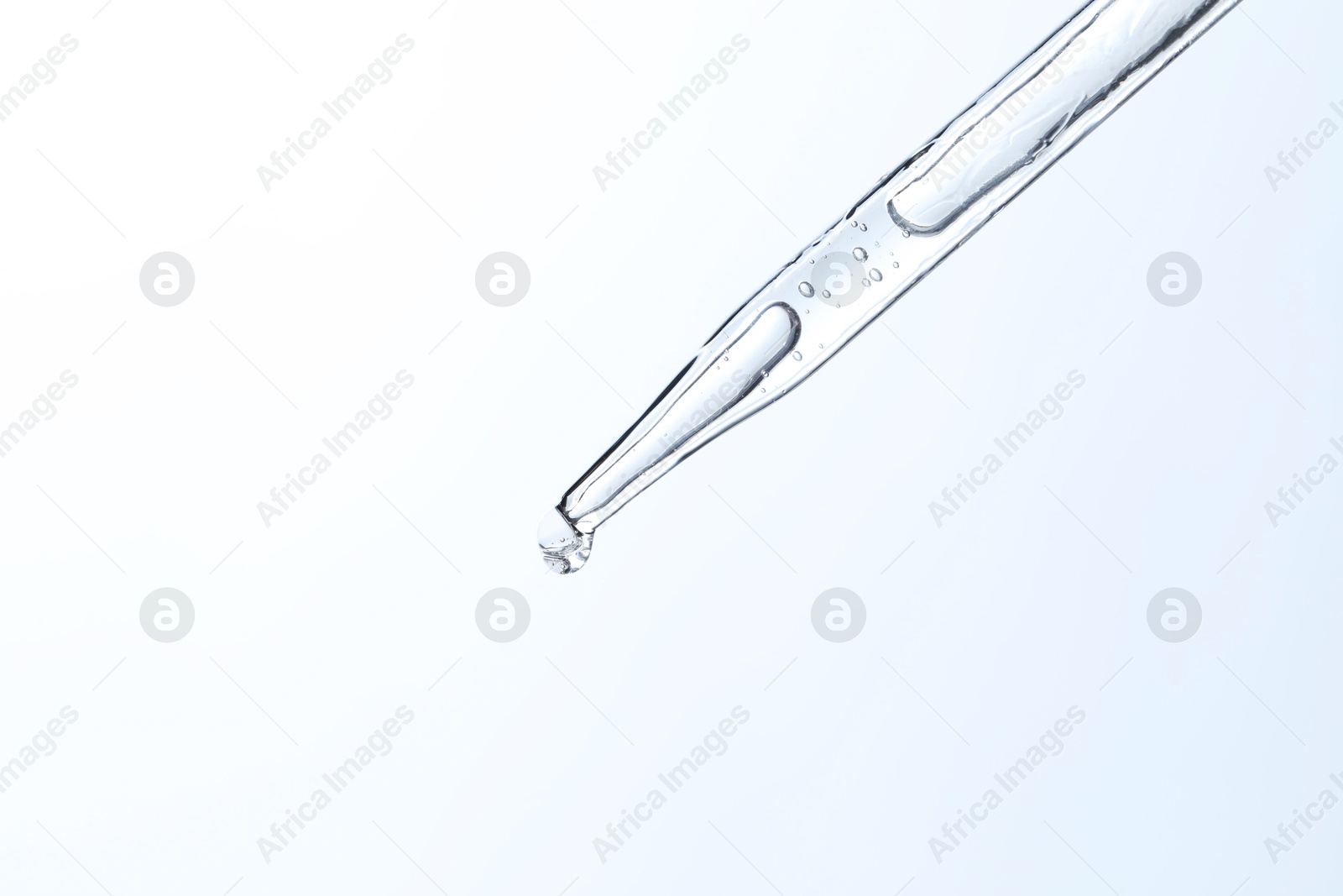 Photo of Dripping liquid from pipette on light blue background, closeup