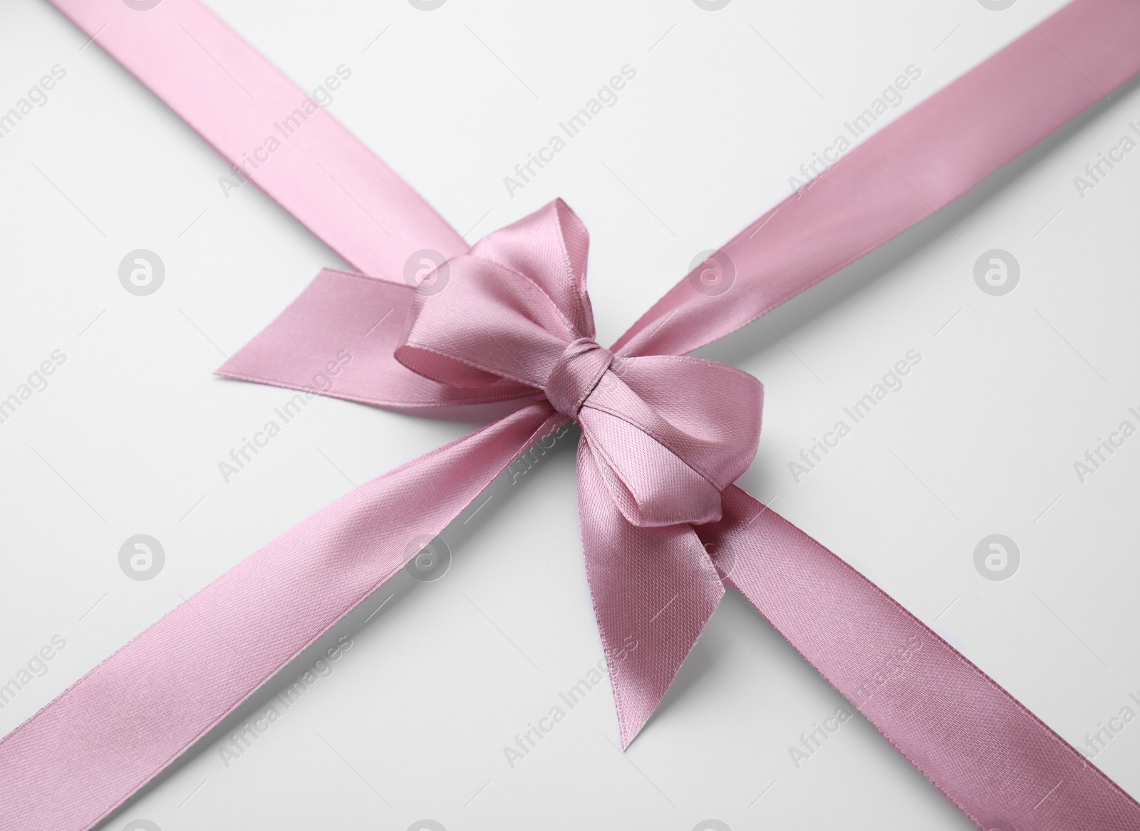 Photo of Pink satin ribbon with bow on white background