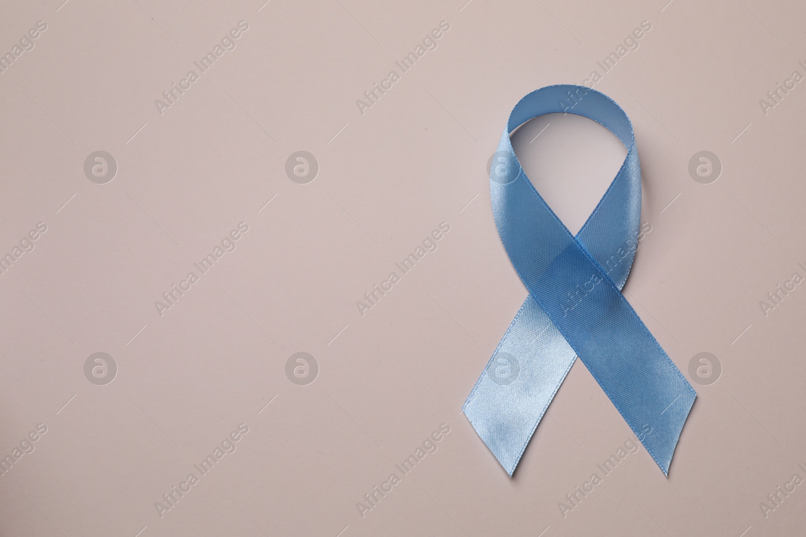 Photo of International Psoriasis Day. Light blue ribbon as symbol of support on beige background, top view. Space for text