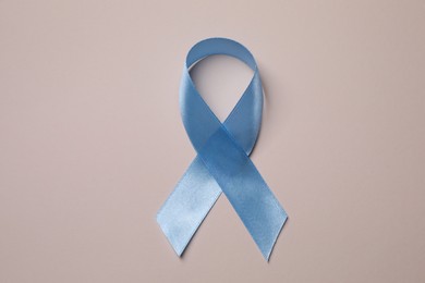 Photo of International Psoriasis Day. Light blue ribbon as symbol of support on beige background, top view