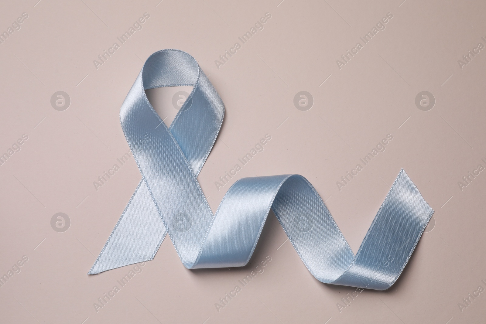 Photo of International Psoriasis Day. Light blue ribbon as symbol of support on beige background, top view