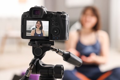 Photo of Happy sports blogger recording fitness lesson at home, focus on camera