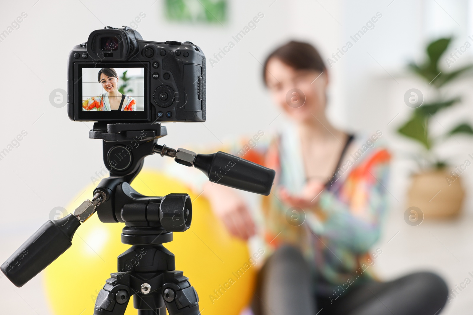 Photo of Happy sports blogger recording fitness lesson at home, focus on camera