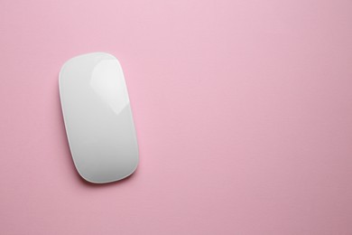 One wireless mouse on pink background, top view. Space for text