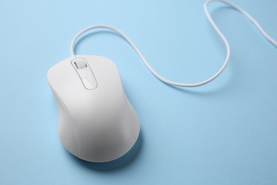 Photo of One wired mouse on light blue background, closeup