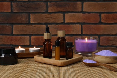 Photo of Different aromatherapy products and burning candles on wooden table